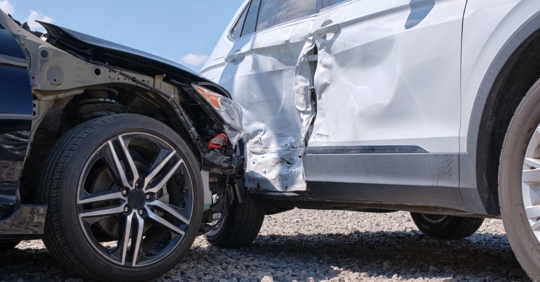 Damaged in heavy car accident vehicles after collision on city street crash site.