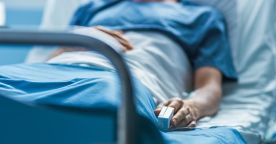 Photo of an unidentifiable man laying in a hospital bed.