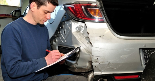 Man taking notes about damage to a car