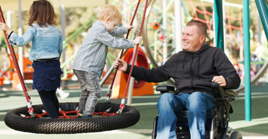 Man in wheelchair playing at park with his kids